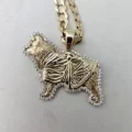 A gold dog pendant with a glittery stone border attached to a gold curb chain.