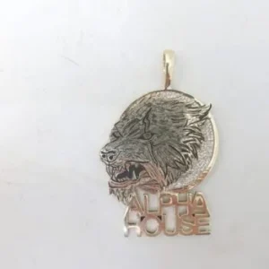 A silver or white gold circular pendant featuring a detailed profile of a snarling wolf's head with the words "ALPHA HOUSE" in block letters at the base.
