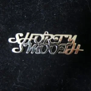A polished silver jewelry pendant featuring the words "Shorty Smooth" in a stylized, interlocking script font.